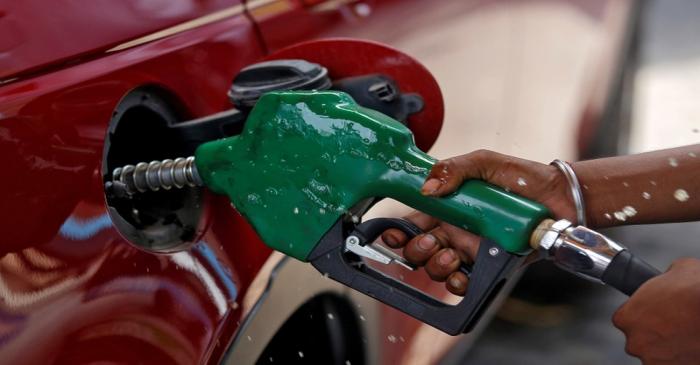 FILE PHOTO: A worker holds a nozzle to pump petrol into a vehicle at a fuel station in Mumbai