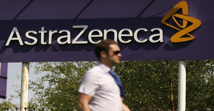 FILE PHOTO - A man walks past a sign at an AstraZeneca site in Macclesfield