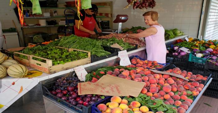 A woman buys fruit and vegetables in a street market in Rome