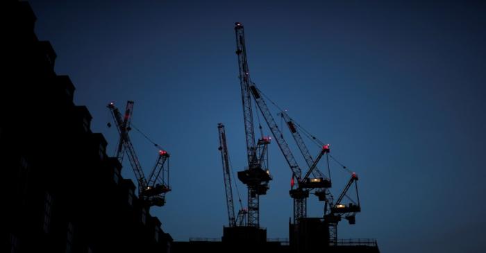 Construction cranes are seen on a building site at sunrise in central London