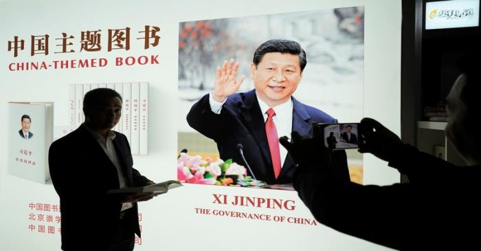 FILE PHOTO: A man poses for pictures at a booth of China's President Xi Jinping books,