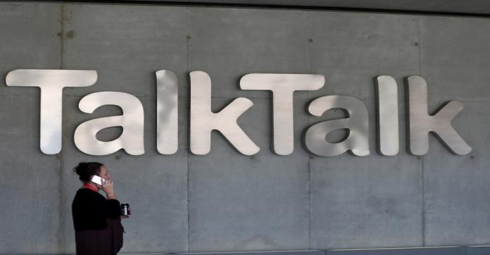 A woman speaks on her phone as she passes a branded logo outside the Talktalk headquarters in