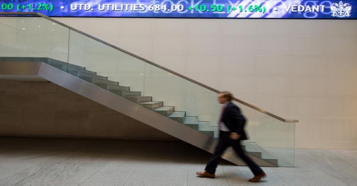 FILE PHOTO:  A man walks under an electronic information board at the London Stock Exchange in