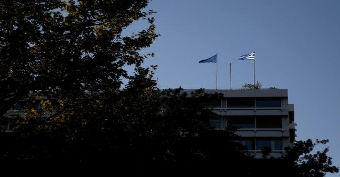 A Greek and a tangled EU flag flutter atop Greece's Financial Ministry in Athens