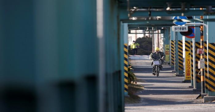 A worker cycles near a factory at the Keihin industrial zone in Kawasaki