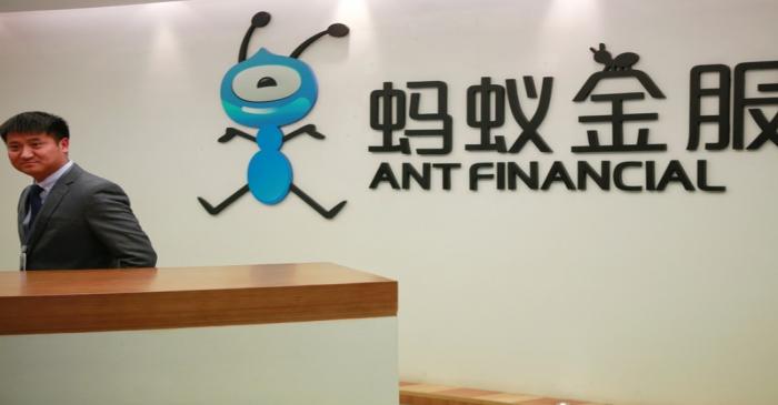 Employee stands next to the logo of Ant Financial Services Group at its headquarters in