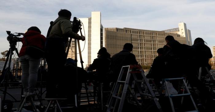 Members of media crews are seen on step ladders in front of the Tokyo Detention Center, where