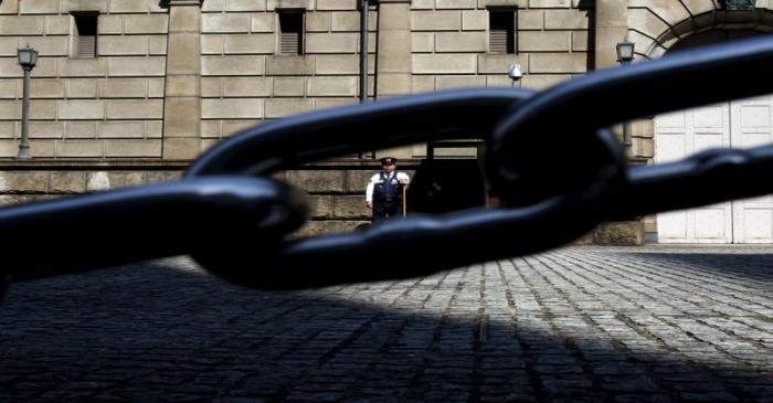 A security officer is seen through a chain link as he stands guard outside the Bank of Japan