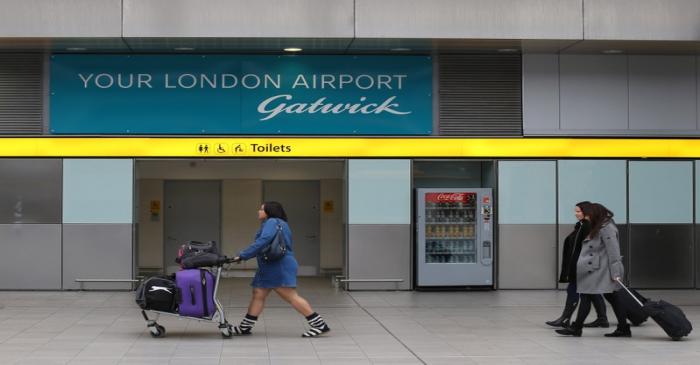 Travellers pass a sign for Gatwick Airport in southern Britain