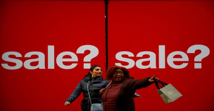 Pedestrians walk past a sign of a shop window in the West End, in London