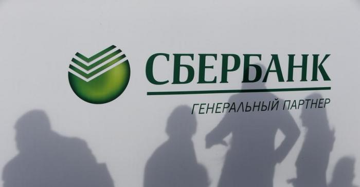 Participants cast their shadows on a board with the logo of Sberbank at the St. Petersburg