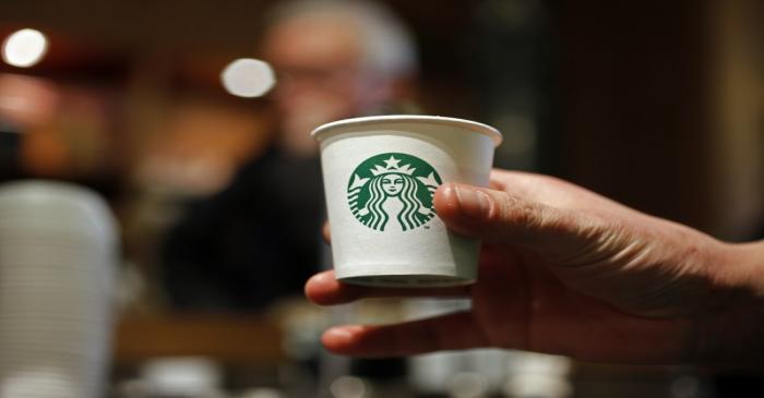 A barista holds a cup of coffee at Starbucks' Vigo Street branch in Mayfair, central London