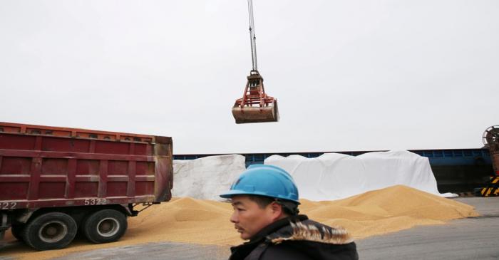 FILE PHOTO: Worker looks on as imported soybeans are transported at a port in Nantong