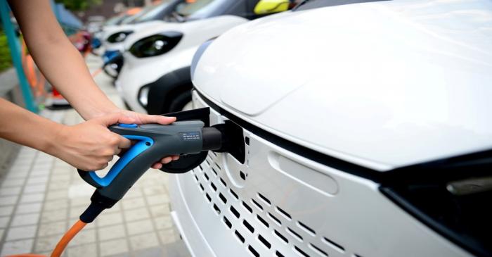 Staff member hooks up a charging cable to EV at a charging station in Liuzhou