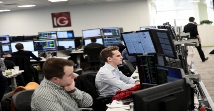 FILE PHOTO:  Traders look at financial information on computer screens on the IG Index trading