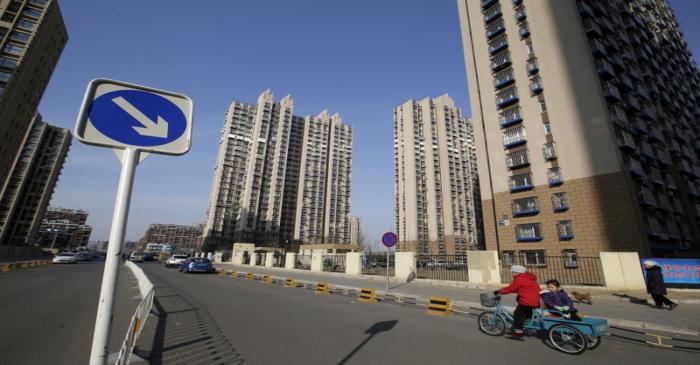 FILE PHOTO: FILE PHOTO: A woman rides a tricycle carrying a child near a residential compound