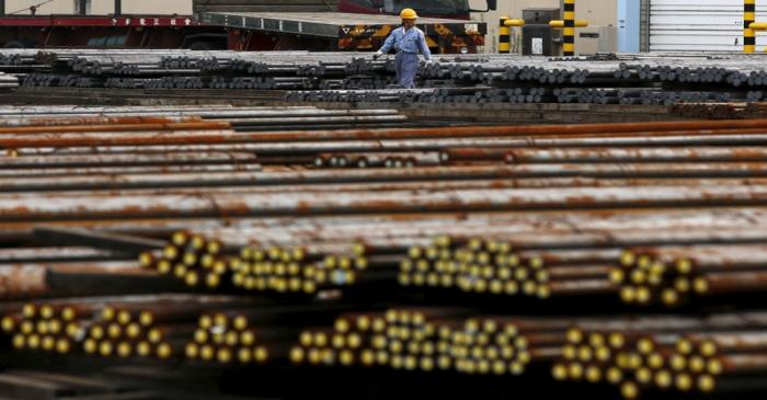 FILE PHOTO: A worker walks among steel rods at a steel collection facility in Tokyo