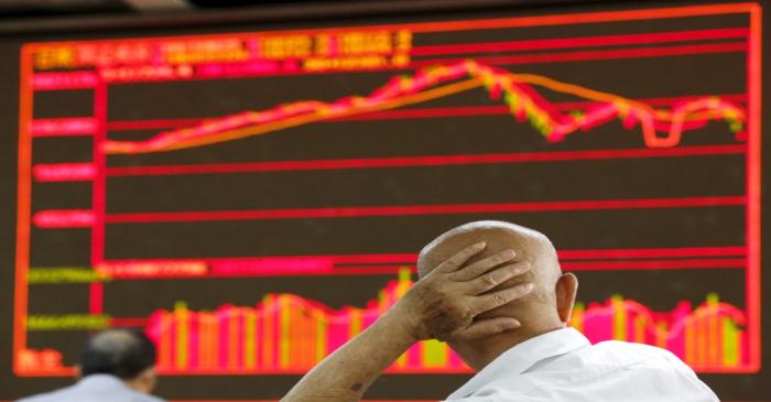 An investor looks at an electronic board showing stock information at a brokerage house in