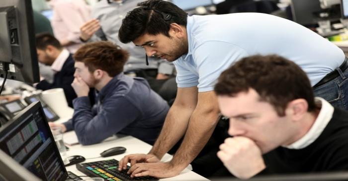 Traders looks at financial information on computer screens on the IG Index trading floor