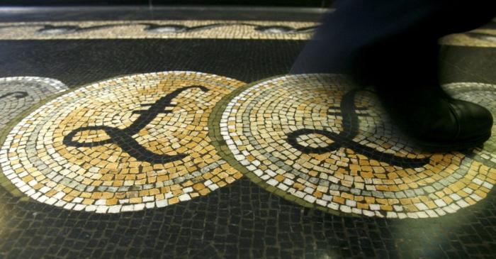 File photograph shows an employee walking over a mosaic depicting pound sterling symbols on the