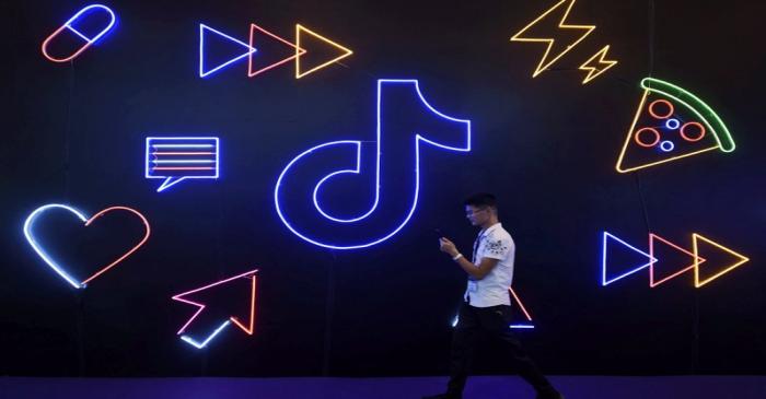 Man walks past a sign of ByteDance's app TikTok, known locally as Douyin, at an expo in