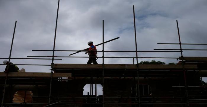 A builder assembles scaffolding as he works on new homes being built for private sale on a