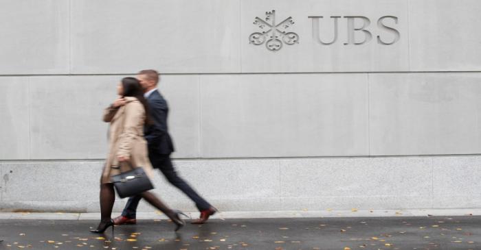 FILE PHOTO: People walk past a logo of Swiss bank UBS in Zurich