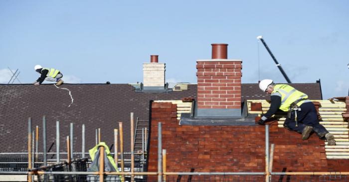 FILE PHOTO: Construction workers work on a Taylor Wimpey housing estate in Aylesbury