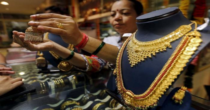 FILE PHOTO: A saleswoman shows a gold earring to customers at a jewellery showroom in Mumbai