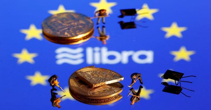 FILE PHOTO: Small toy figures are seen on representations of the Libra virtual currency logo