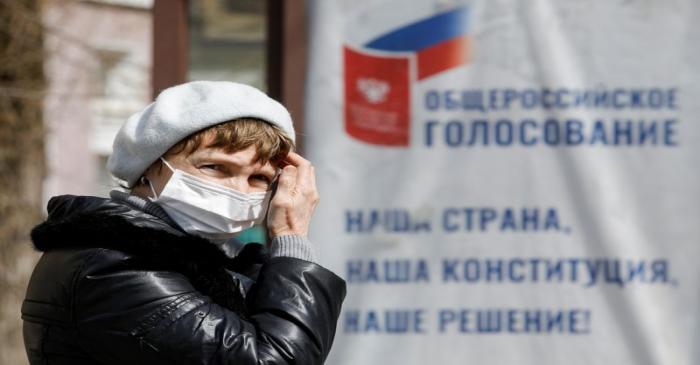 FILE PHOTO: A woman wearing a protective mask near a board informing of a nationwide vote on