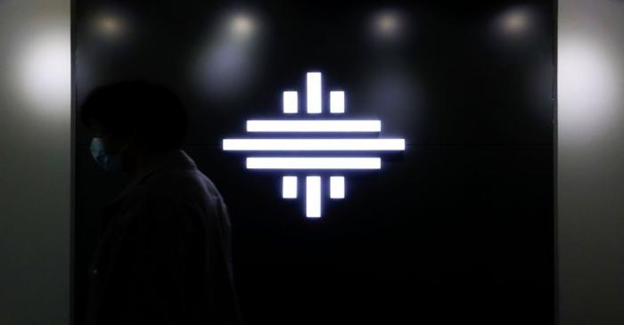 A man wearing a face mask walks past a logo of autonomous truck startup Inceptio Technology at