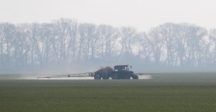 FILE PHOTO: An agricultural worker drives a tractor spreading fertilizers to a field of winter