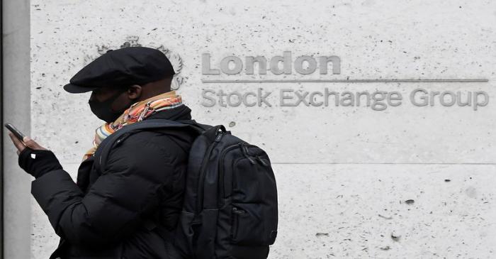 A man wearing a protective face mask walks past the London Stock Exchange Group building in the