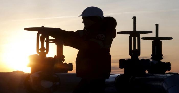 FILE PHOTO: Worker checks valve of oil pipe at Lukoil company owned Imilorskoye oil field