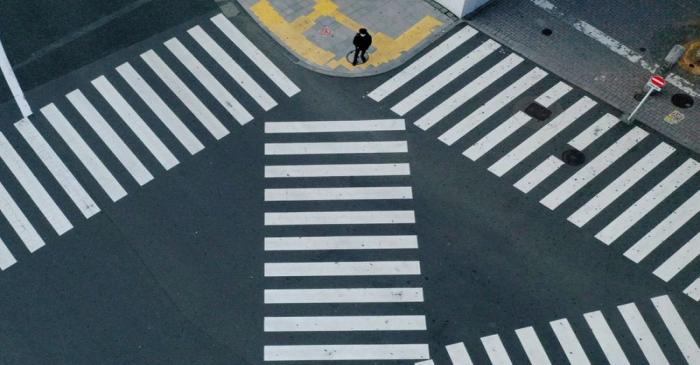 A man waits to cross a street in front of Shinjuku station in Tokyo