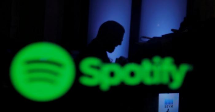 FILE PHOTO: A trader is reflected in a computer screen displaying the Spotify brand before the