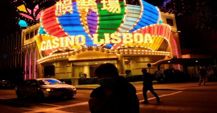 People wearing masks walk in front of Casino Lisboa before its temporary closing following the