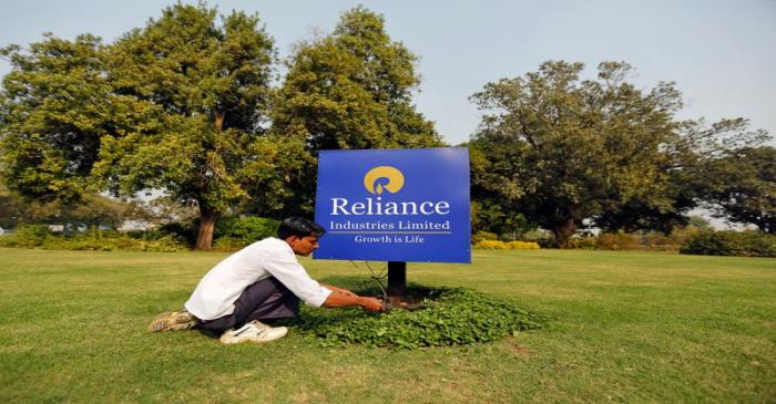 FILE PHOTO: A gardener works next to a board of Reliance Industries Ltd at Gandhinagar in