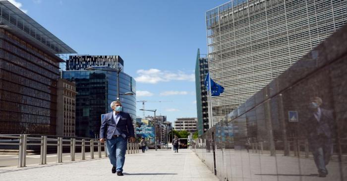 A man wearing a face mask walks past the European Commission headquarters as the spread of