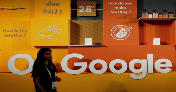 FILE PHOTO: A woman walks past the logo of Google during an event in New Delhi