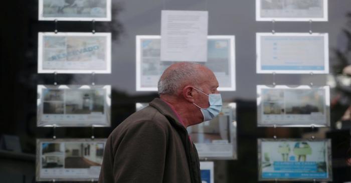 FILE PHOTO: A man wearing a protective face mask walks past a real estate agency during the