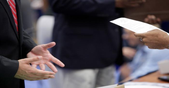 FILE PHOTO:  A job seeker talks with a corporate recruiter as he peruses the man's resume at a