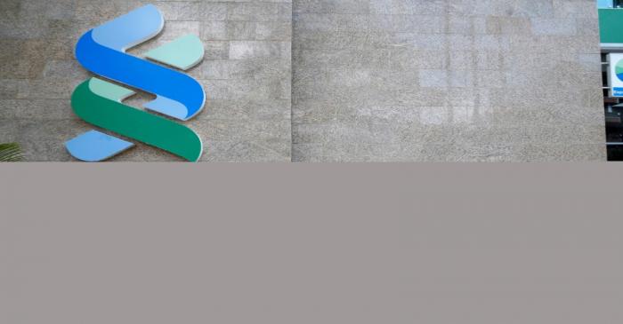 FILE PHOTO: A man walks past a logo of the Standard Chartered Kenya bank in their main office