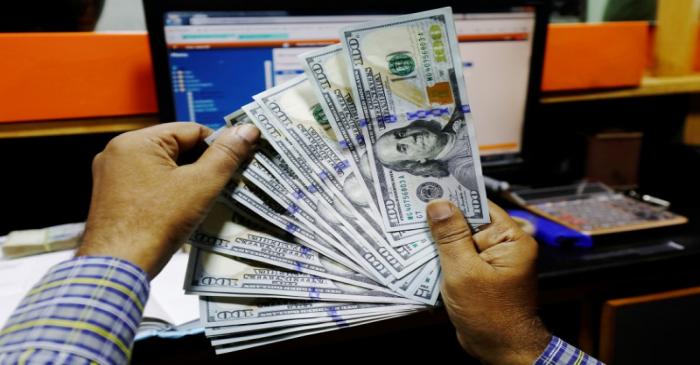 A trader shows U.S. dollar notes at a currency exchange booth in Karachi