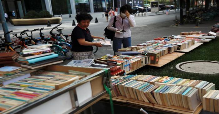 Street vendor sorts books at her stall at the Sanlitun shopping area in Beijing