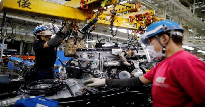 FILE PHOTO: Employees wearing protective face masks and face guards work on the automobile