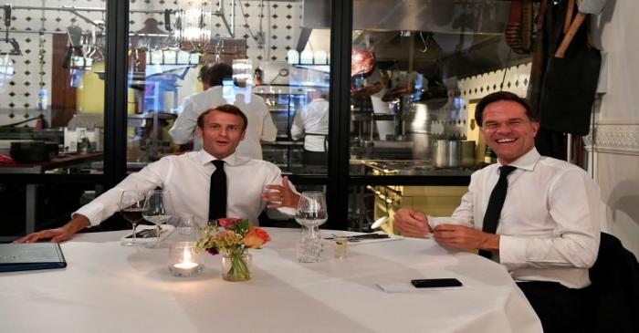 French President Emmanuel Macron and Dutch Prime Minister Mark Rutte react in a restaurant, in