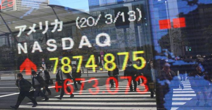 FILE PHOTO: People wear protective face masks as they are reflected in a stock quotation board