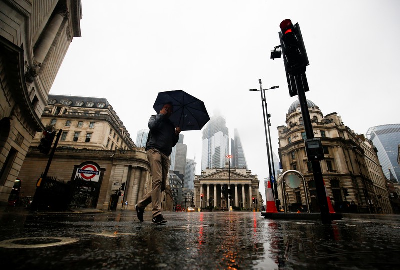 People walk through the financial district during rainy weather in London